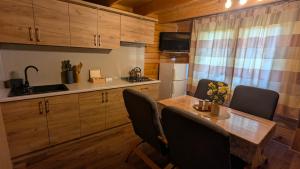 a kitchen with a wooden table and chairs and a kitchen with a sink at DAGA-Domki Nad Soliną in Solina +11 photos