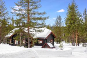 a cabin with snow on the roof in the woods at Orrenkolo, Lapland in Luosto
