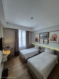 a hotel room with two beds and a desk at Expressia Hotel Makassar in Makassar