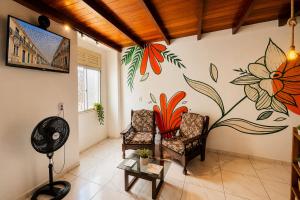 a living room with two chairs and a flower mural on the wall at Residência Ilha Bela - Casa Inteira no Centro Histórico de São Luís in São Luís