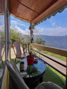 a table and chairs on a balcony with a view at Dawaipani Sona Homestay in Jālāpahār