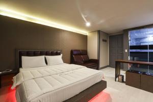 a bedroom with a large bed and a chair at 세븐호텔 in Daegu