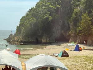 a group of tents on a beach next to the ocean at 伊豆ビーチクラブ in Shimoda