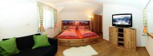 Bett in einem Zimmer mit Sofa und TV in der Unterkunft Obermühle in Rauris