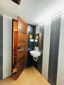 a bathroom with a sink and a wooden door at Fort Grande ONE in Cochin