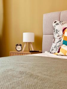 a bed with a lamp and a clock on a night stand at Central Apartment in Kyustendil +14 photos