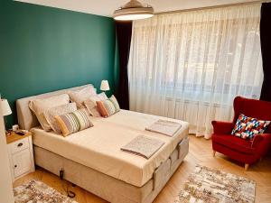 a bedroom with a large bed and a red chair at Central Apartment in Kyustendil