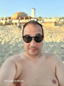 ein Mann mit freiem Oberkörper und Sonnenbrille am Strand in der Unterkunft Riyadh palms in Constantine
