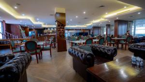 a restaurant with couches and tables and chairs at Shaheen Hotel Baghdad in Baghdād