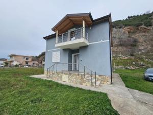 a blue house with a balcony on the side of it at Vila Elbasan in Labinot i Poshtëm