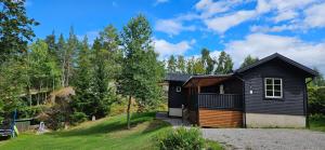 a black house on a hill with trees at Villa Blackberry, nära Kolmården & Norrköping in Åby