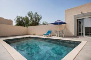 a swimming pool with a chair and an umbrella at Villas avec piscine in Taguermess