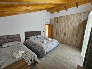 two beds in a room with wooden ceilings at Vila Elbasan in Labinot i Poshtëm