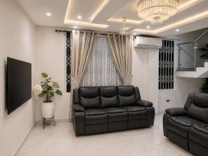 a living room with a leather couch and a chandelier at Kingdom homes in Amanfro