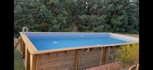 a large swimming pool with a wooden fence and trees at Gîte Le Pré Doux in Ambert