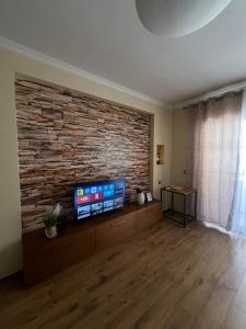 a living room with a stone wall and a flat screen tv at Casa Trio in Tirana