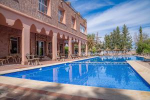 a pool with tables and chairs next to a building at Diar illi in Touama