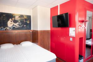 a bedroom with a red wall with a bed and a tv at Omena Hotel Helsinki City Centre in Helsinki