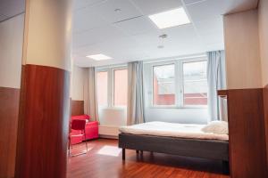 a bedroom with a bed and a red chair at Omena Hotel Helsinki City Centre in Helsinki