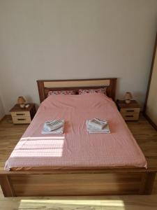 a bed with pink sheets and two towels on it at Village house Tea in Virpazar