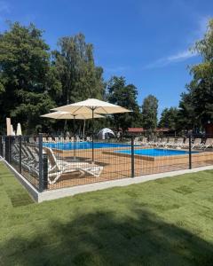 a fence with an umbrella next to a swimming pool at Rewita Mielno Harmonia in Mielno +22 photos