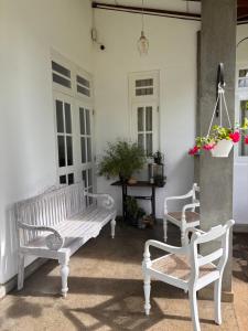 two white benches sitting on a porch with flowers at Villa Aureia in Bandarawela
