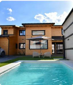 a house with a swimming pool and an umbrella at Casa rural El Pinton in Gálvez