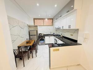 a kitchen with white cabinets and a wooden table at Manifique renovated apartment Marrakech in Marrakesh