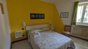 a bedroom with a bed and a yellow wall at Sirena Vista Lago in Stresa