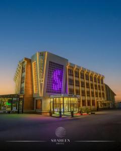 a large building with a purple sign on it at Shaheen Hotel Baghdad in Baghdād