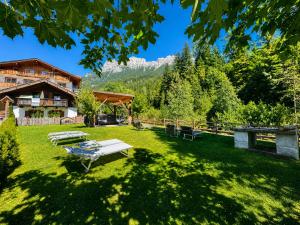 a park with benches in the grass in front of a lodge at Park Hotel Avisio in Soraga