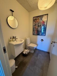 a bathroom with a sink and a toilet and a mirror at Hyggeligt hus. in Holstebro +42 photos