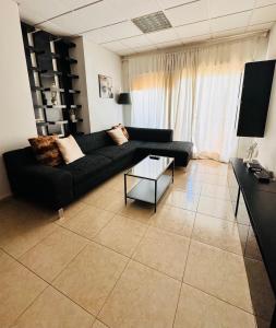 a living room with a black couch and a table at Stylish Apartment with Spacious Terrace in Aglantzia