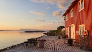 a woman standing on a dock next to a red building at Handelsstedet Forvik in Vevelstad