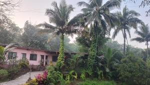 a house with two palm trees in front of it at Vitthal prema nivas in Sawantwadi