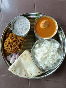 a plate of food with rice and a bowl of soup at Vitthal prema nivas in Sawantwadi