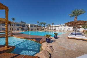 a swimming pool with an umbrella and a resort at Reef Oasis Beach Aqua Park Resort in Sharm El Sheikh