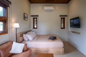 a bedroom with a bed and a couch and a tv at The BROWN PAI in Pai