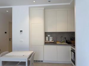 a kitchen with white cabinets and a white table at Charming studio-plus in Lustica Bay Centrale in Radovici