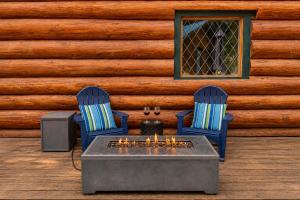 two chairs and a table in front of a log wall at Soaring Pines Lodge by NW Comfy Cabins in Leavenworth