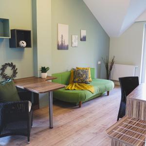 a living room with a green couch and a table at Rosenhotel - Serviced Apartments in Zwentendorf
