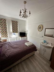 a bedroom with a bed and a sink and a chandelier at Catherine Lodge Finchley in Whetstone