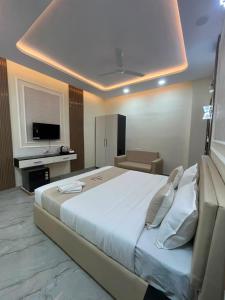 a bedroom with a large white bed and a television at Hotel Shanvi Inn in Jabalpur