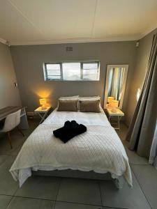 a bedroom with a white bed with a black shirt on it at Klein Escape in Wilderness