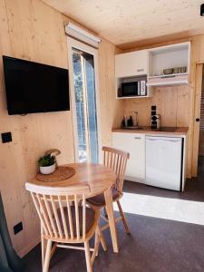 a kitchen and dining room with a wooden table and chairs at Les Deux M Tiny House with Private Garden in Sorgues