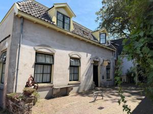 an old white house with a gate in front of it at Hanzestadslogement "De Leeuw", logies in het centrum van Deventer in Deventer