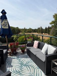a patio with a couch and an umbrella and flowers at Burford Lodge - Adults only in Burford