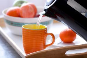 a person pouring juice into a orange cup on a tray at City Centre Cosy Apartments in Budapest