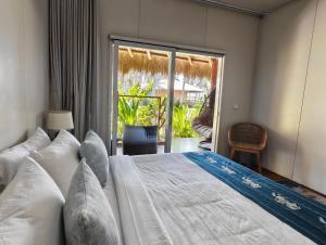 a bedroom with a large bed and a balcony at Sumba Retreat Kerewe in Waikabubak