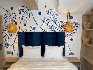 a bedroom with a blue headboard with blue flowers on the wall at Mama Souiri Hotel in Essaouira